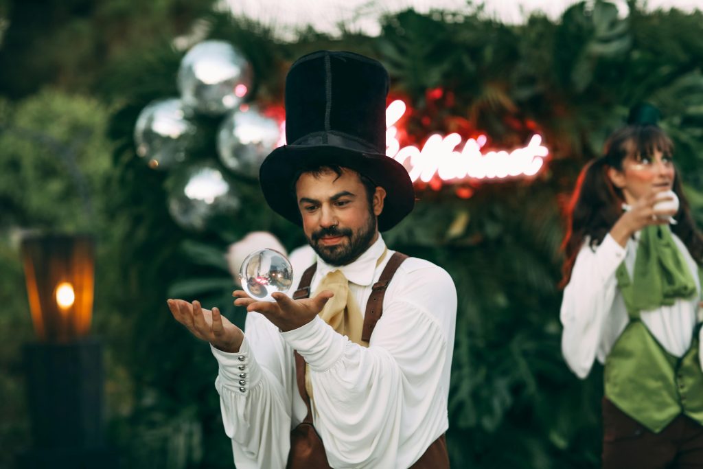 Magician demonstrates a captivating crystal ball trick during an enchanting outdoor event.