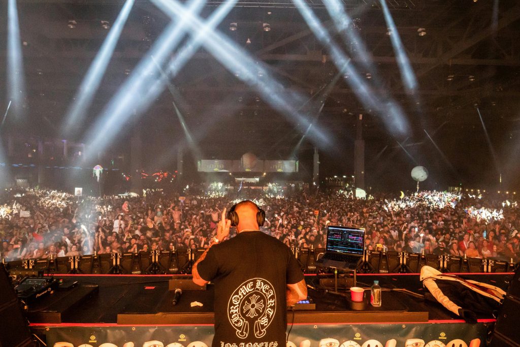 A DJ captivates a massive crowd in a vibrant nightclub performance with dynamic lighting.