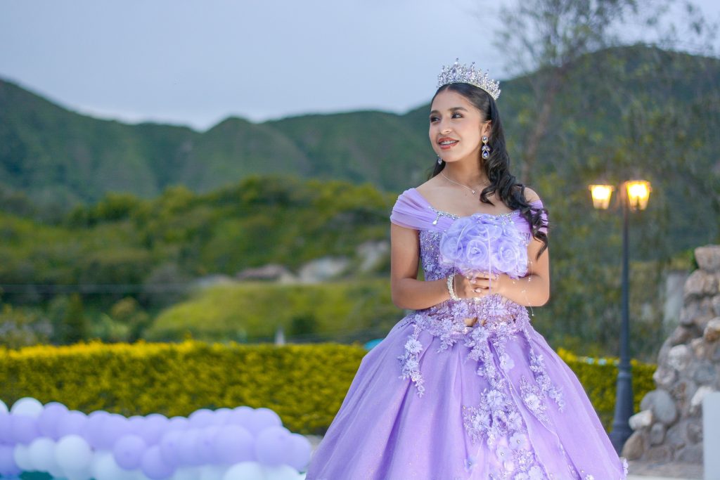 Young woman in a purple ball gown enjoying a special outdoor event with scenic mountain views.