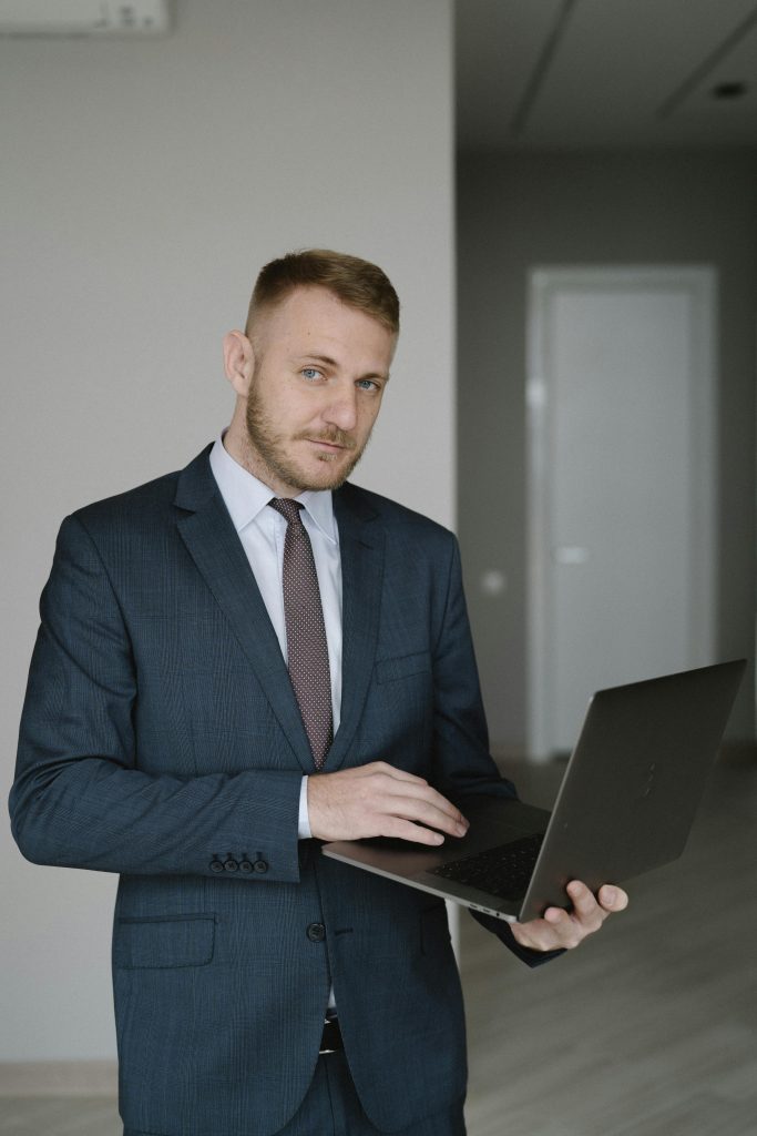 Young businessman in a suit using a laptop indoors, embodying corporate professionalism.